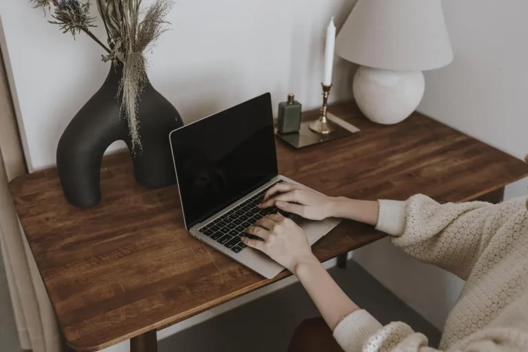 Poručivanje nameštaja preko laptopa za drvenim stolom.